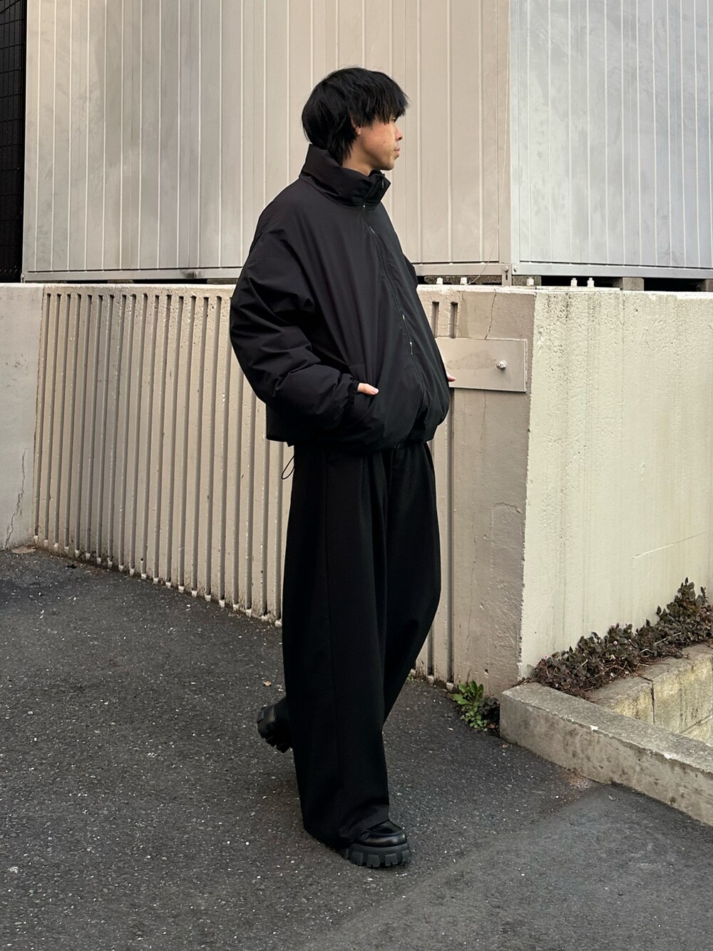 ブラック系のダウンジャケット/コート、ホワイト系のTシャツ/カットソー、ブラック系のスラックスを着用したメンズの冬コーディネートの4枚目の写真