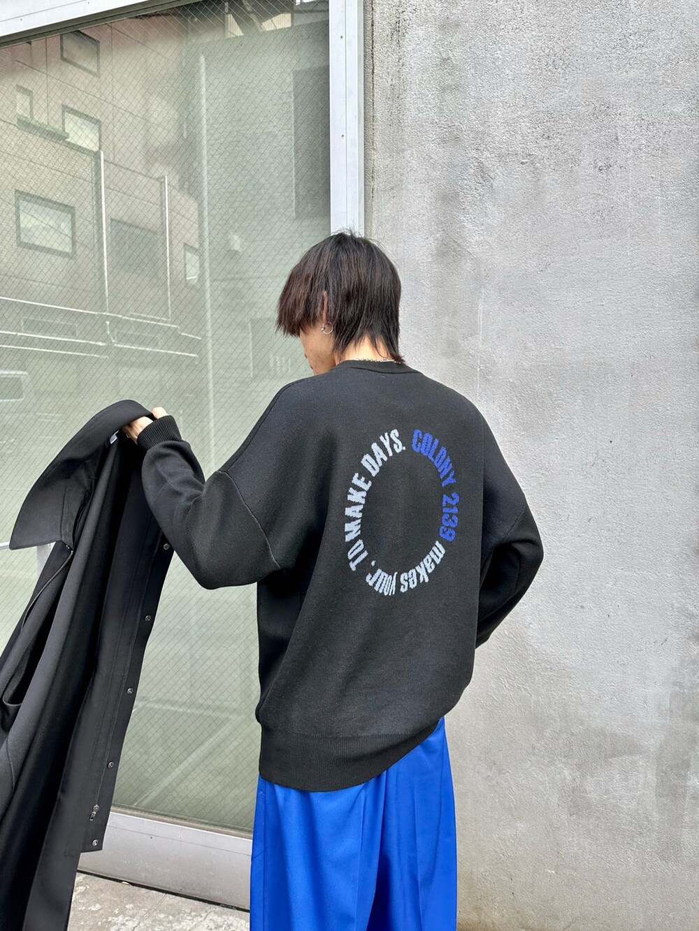 ブラック系のステンカラーコート、ブラック系のニット/セーター、ブルー系のその他パンツを着用したメンズの冬コーディネートの2枚目の写真