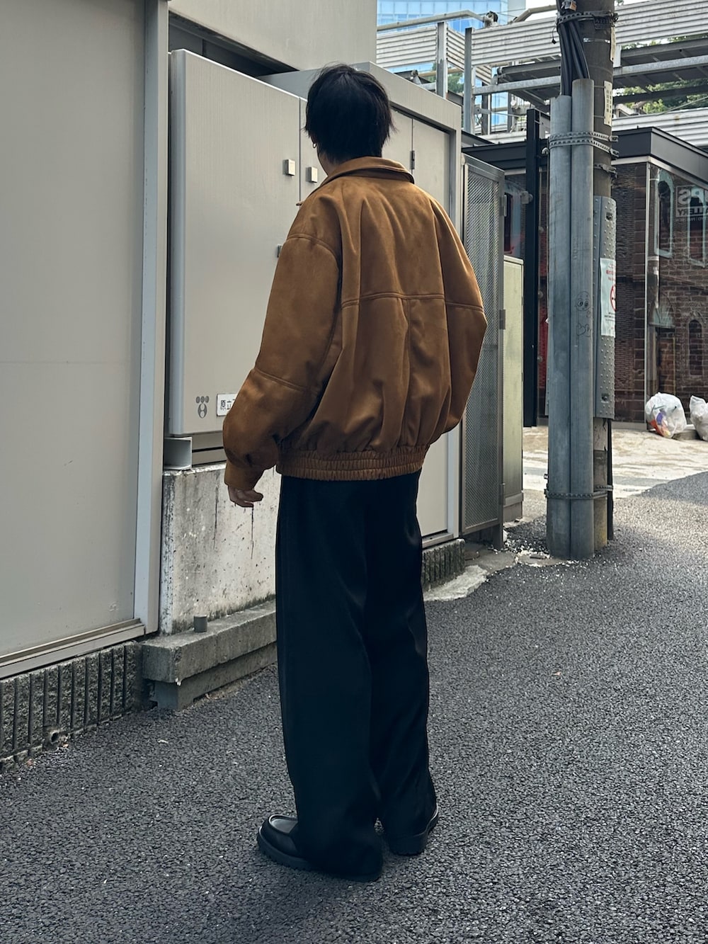 イエロー系のブルゾン、ブラック系のスラックス、ホワイト系のTシャツ/カットソーを着用したメンズの秋コーディネートの3枚目の写真