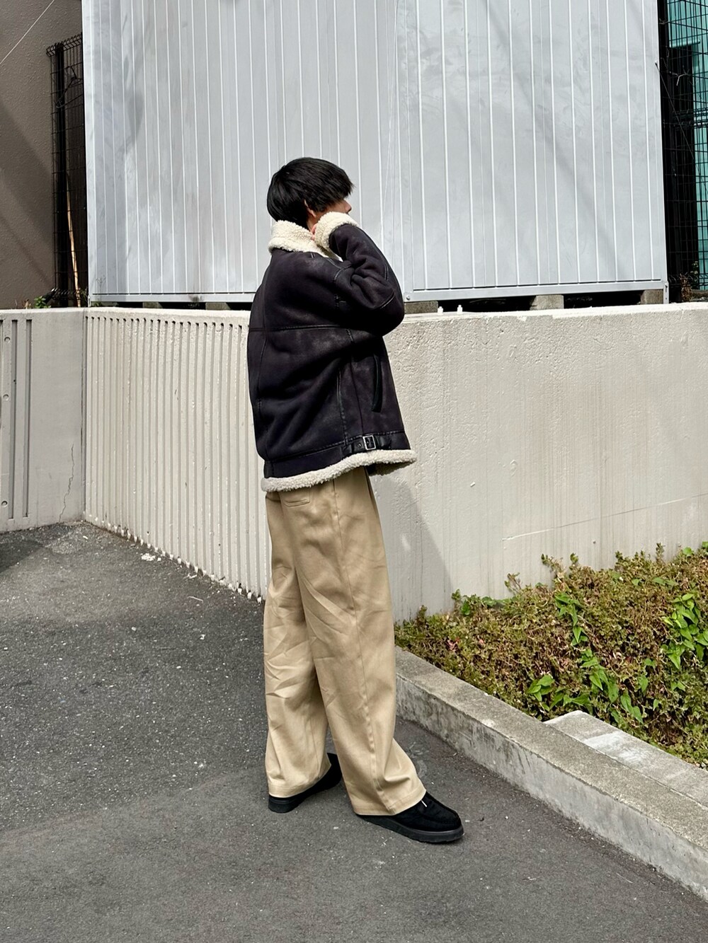ブラック系のムートンコート、ベージュ系のその他パンツ、ブラック系のモカシン/デッキシューズを着用したメンズの秋コーディネートの3枚目の写真