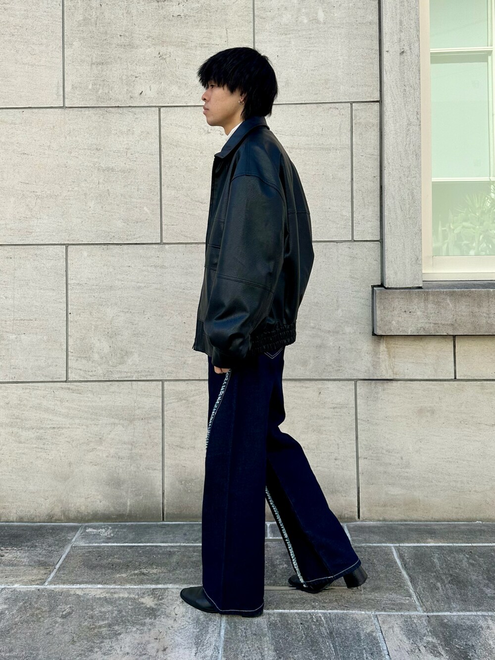 ブラック系のブルゾン、ホワイト系のTシャツ/カットソー、ブルー系のデニムパンツを着用したメンズの秋コーディネートの2枚目の写真