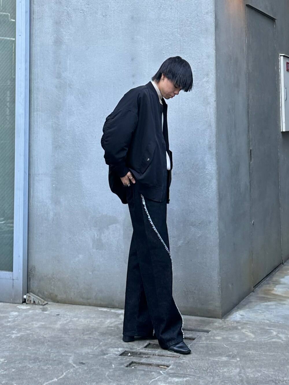 ブラック系のMA-1、ブラック系のデニムパンツ、ベージュ系のニット/セーターを着用したメンズの秋コーディネートの2枚目の写真
