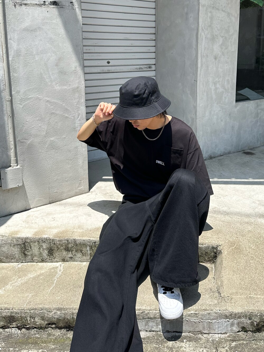 ブラック系のデニムパンツ、ホワイト系のスニーカー、ブラック系のTシャツ/カットソーを着用したメンズの夏コーディネートの2枚目の写真