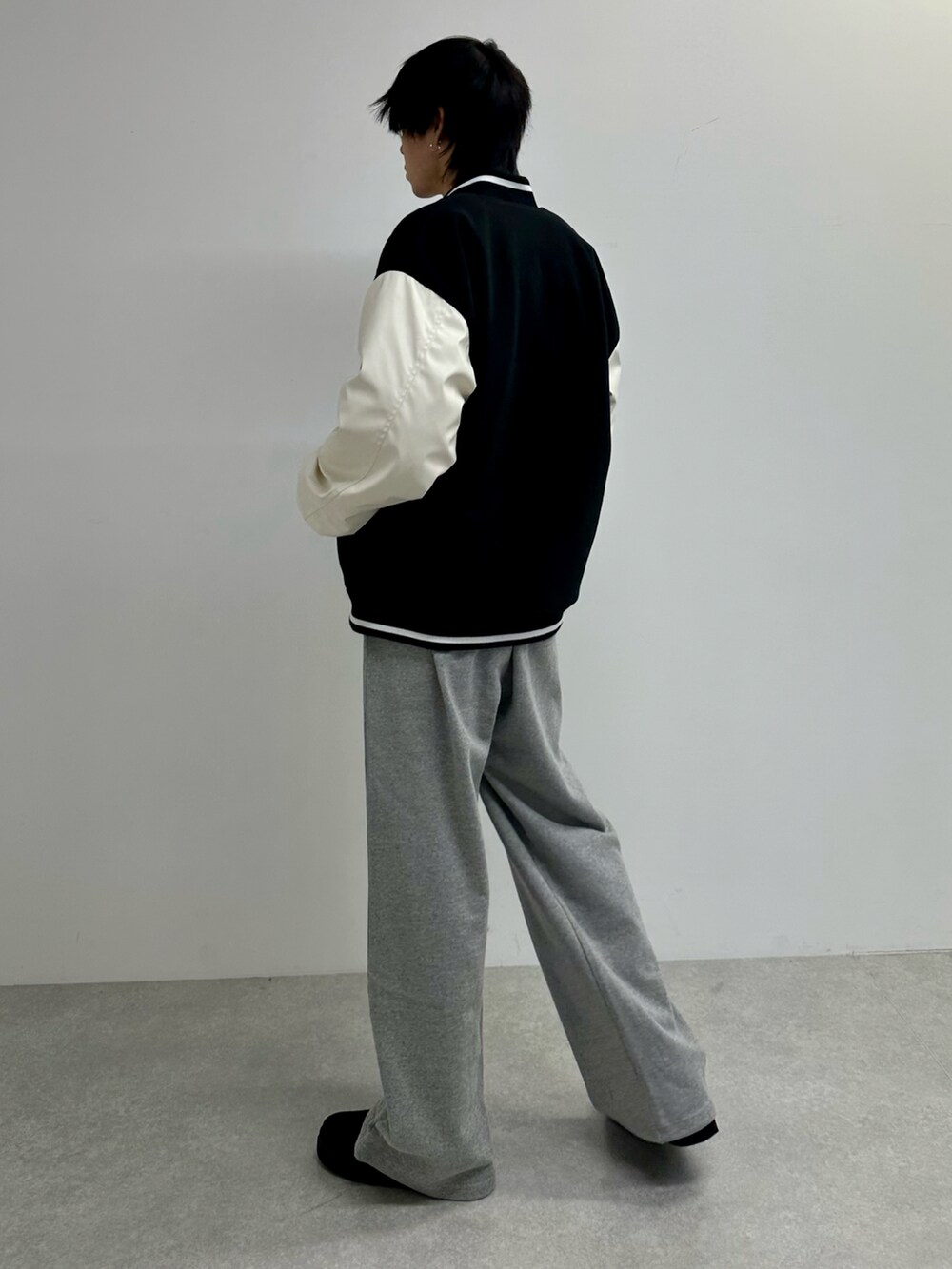 ブラック系のスタジャン、グレー系のスウェットパンツ、ブラック系のモカシン/デッキシューズを着用したメンズの秋コーディネートの3枚目の写真