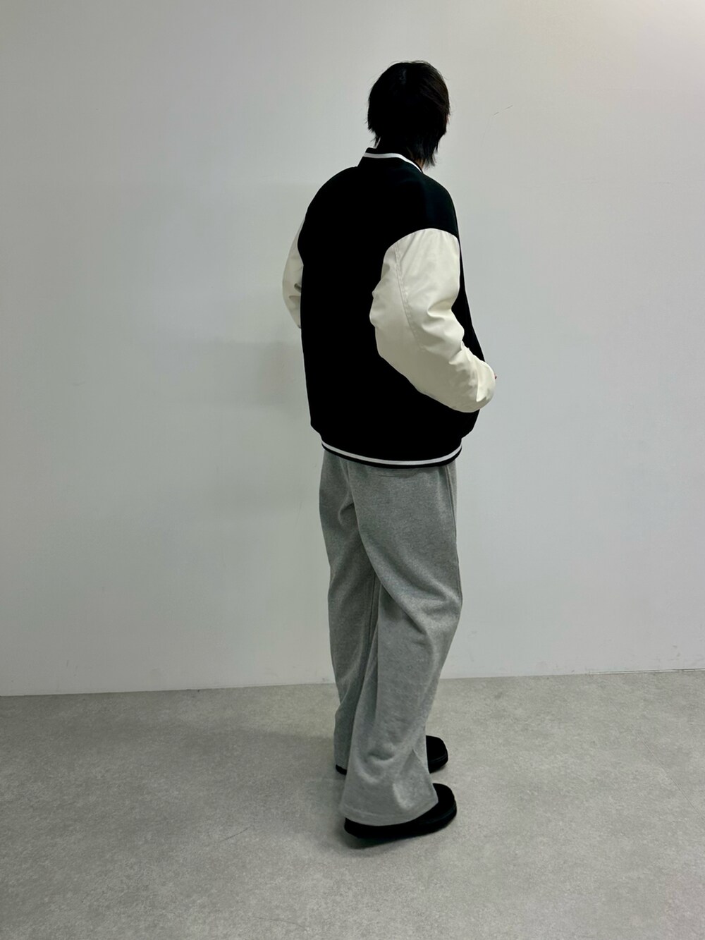 ブラック系のスタジャン、グレー系のスウェットパンツ、ブラック系のモカシン/デッキシューズを着用したメンズの秋コーディネートの2枚目の写真