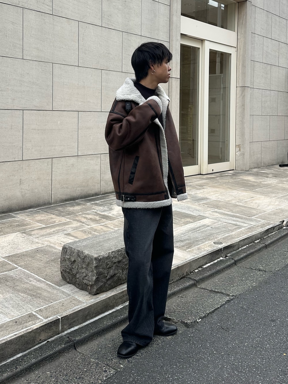 ブラウン系のムートンコート、ブラック系のTシャツ/カットソー、ブラック系のデニムパンツを着用したメンズの秋コーディネートの4枚目の写真