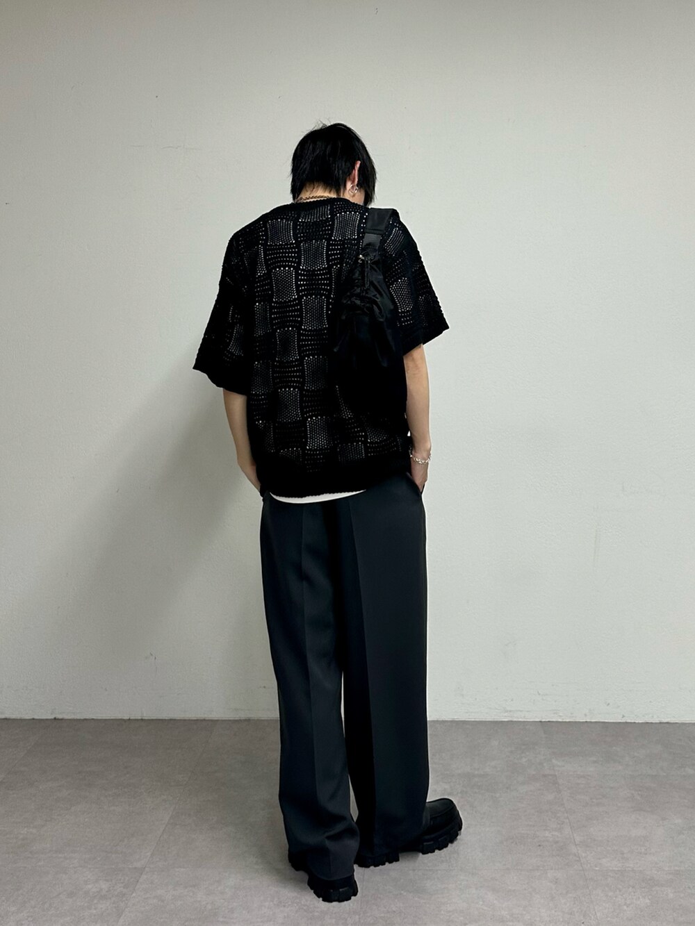 ブラック系のニット/セーター、グレー系のスラックス、ブラック系のショルダーバッグを着用したメンズの春コーディネートの3枚目の写真