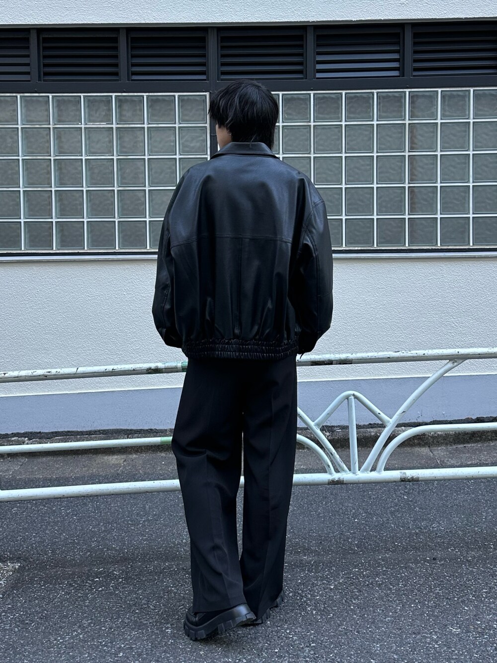 ブラック系のブルゾン、ブラック系のTシャツ/カットソー、ブラック系のスラックスを着用したメンズの冬コーディネートの3枚目の写真