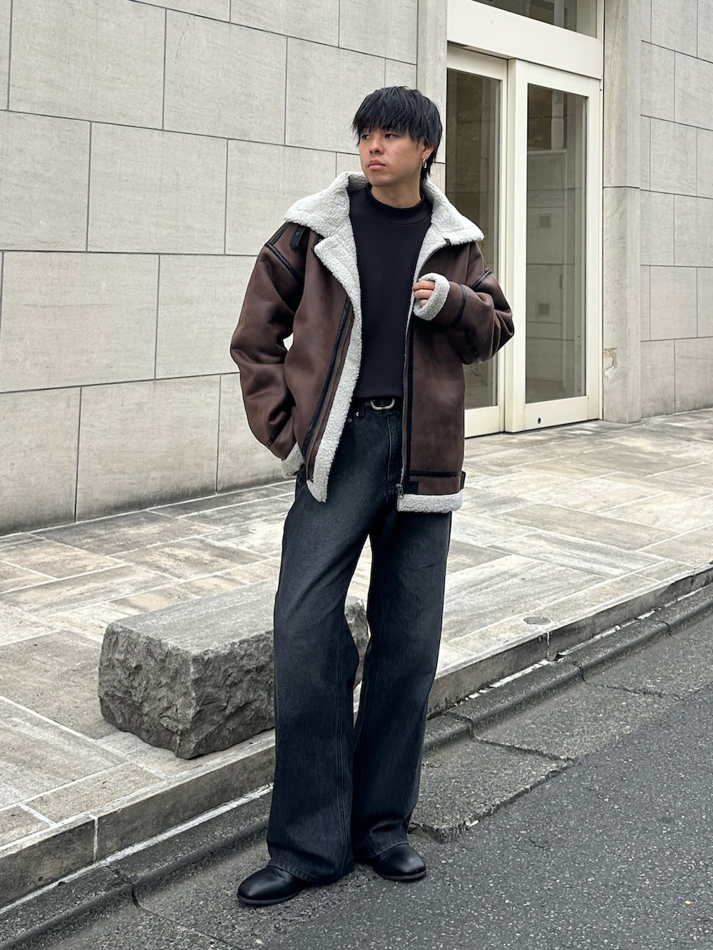 ブラウン系のムートンコート、ブラック系のTシャツ/カットソー、ブラック系のデニムパンツを着用したメンズの秋コーディネートの5枚目の写真