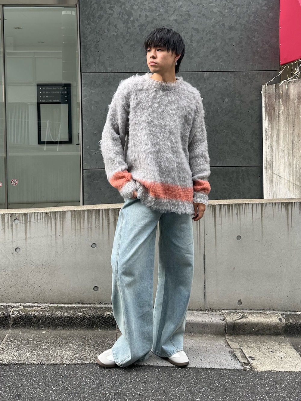 グレー系のニット/セーター、ブルー系のデニムパンツ、ホワイト系のスニーカーを着用したメンズの秋コーディネートの2枚目の写真