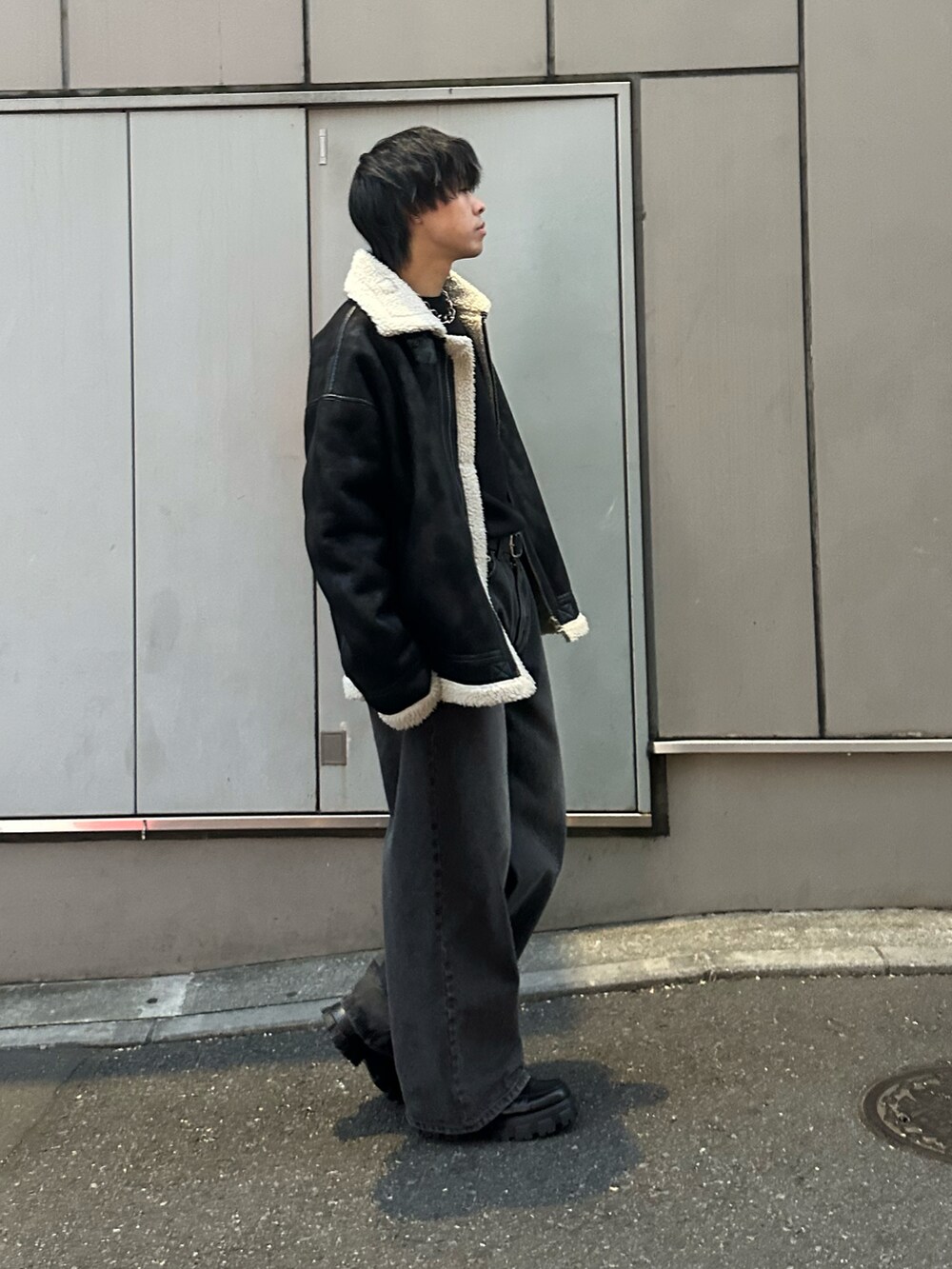 ブラック系のムートンコート、ブラック系のニット/セーター、ブラック系のデニムパンツを着用したメンズの冬コーディネートの2枚目の写真