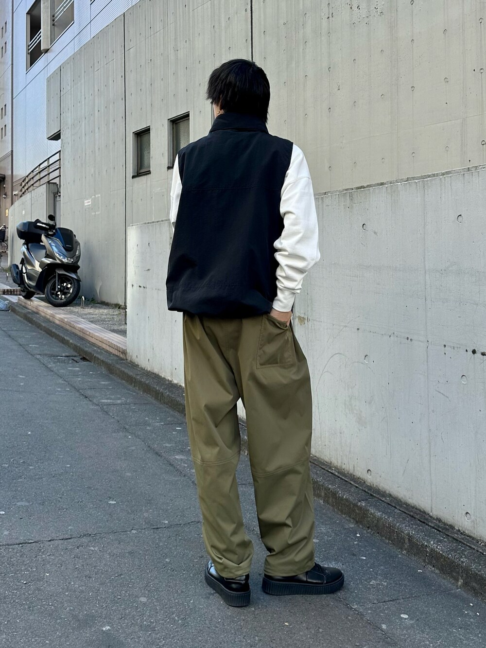 ブラック系のベスト、グリーン系のその他パンツ、ホワイト系のスウェットを着用したメンズの春コーディネートの2枚目の写真