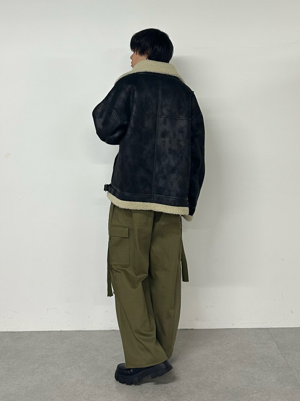 ブラック系のムートンコート、グリーン系のカーゴパンツ、ブラック系のTシャツ/カットソーを着用したメンズの秋コーディネートの3枚目の写真