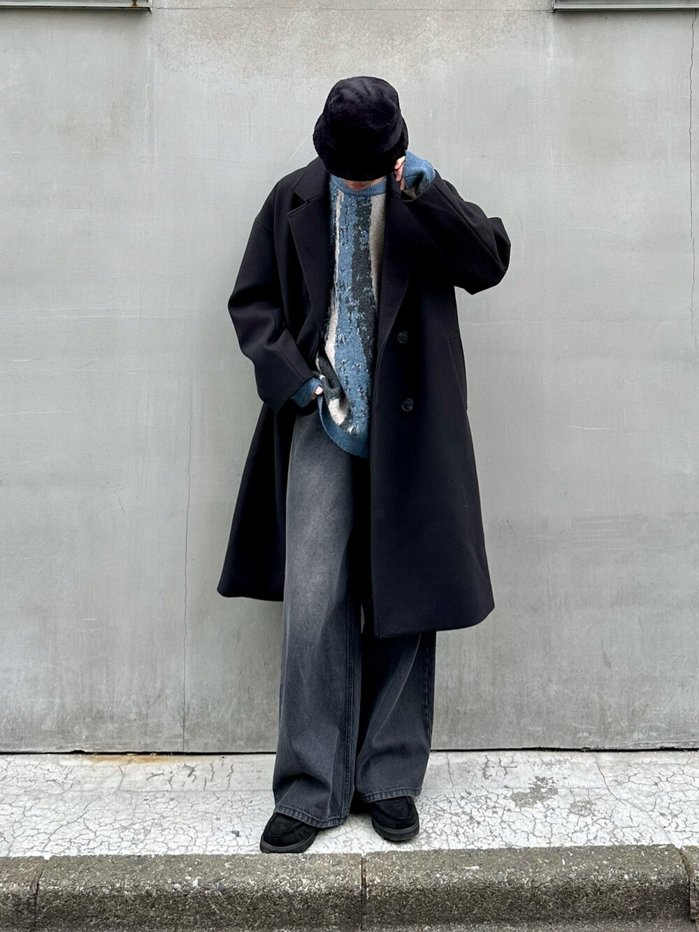 ブラック系のその他アウター、ブラック系のデニムパンツ、ブルー系のニット/セーターを着用したメンズの冬コーディネートの2枚目の写真