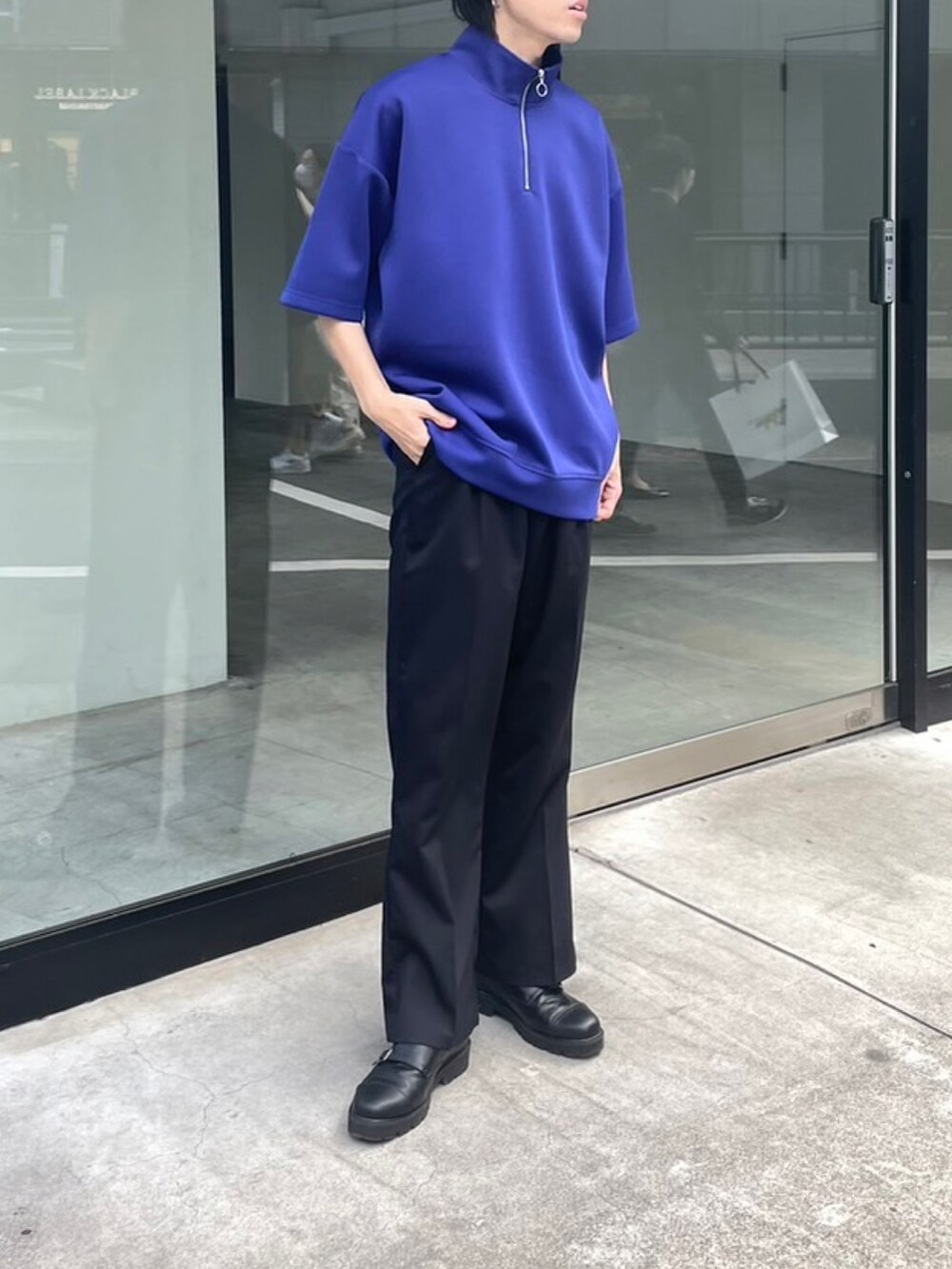 ブルー系のTシャツ/カットソー、ブラック系のスラックスを着用したメンズの春コーディネートの2枚目の写真