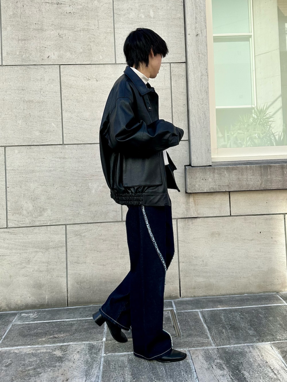 ブラック系のブルゾン、ホワイト系のTシャツ/カットソー、ブルー系のデニムパンツを着用したメンズの秋コーディネートの3枚目の写真