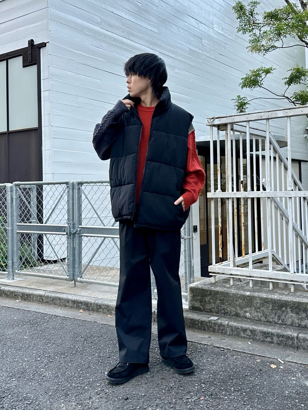 ブラック系のダウンベスト、オレンジ系のニット/セーター、ブラック系のその他パンツを着用したメンズの冬コーディネートの3枚目の写真