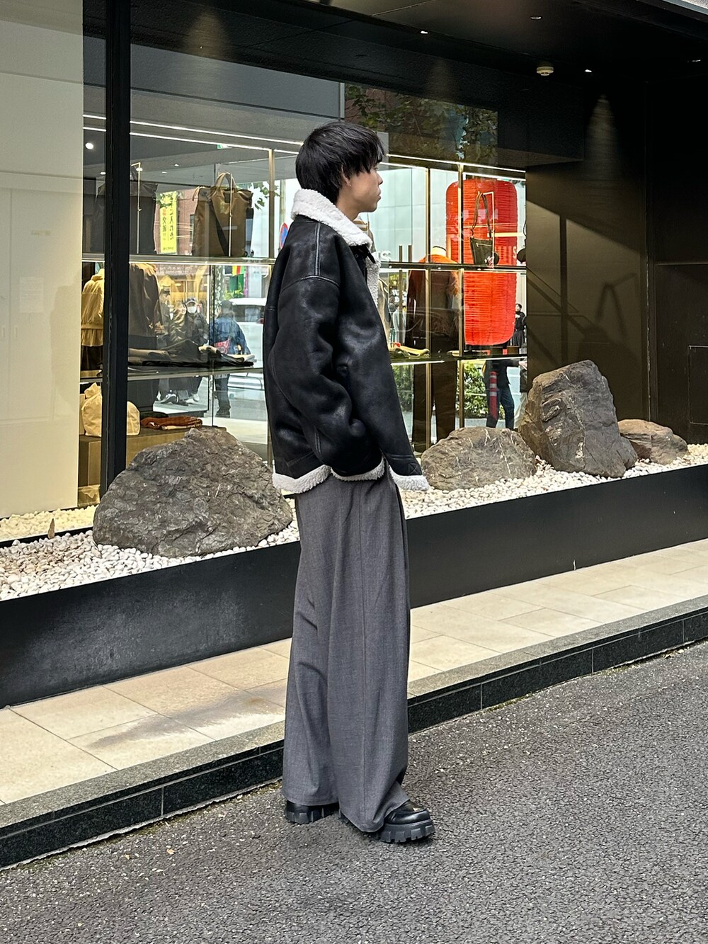 ブラック系のムートンコート、ブラック系のTシャツ/カットソー、グレー系のスラックスを着用したメンズの冬コーディネートの2枚目の写真