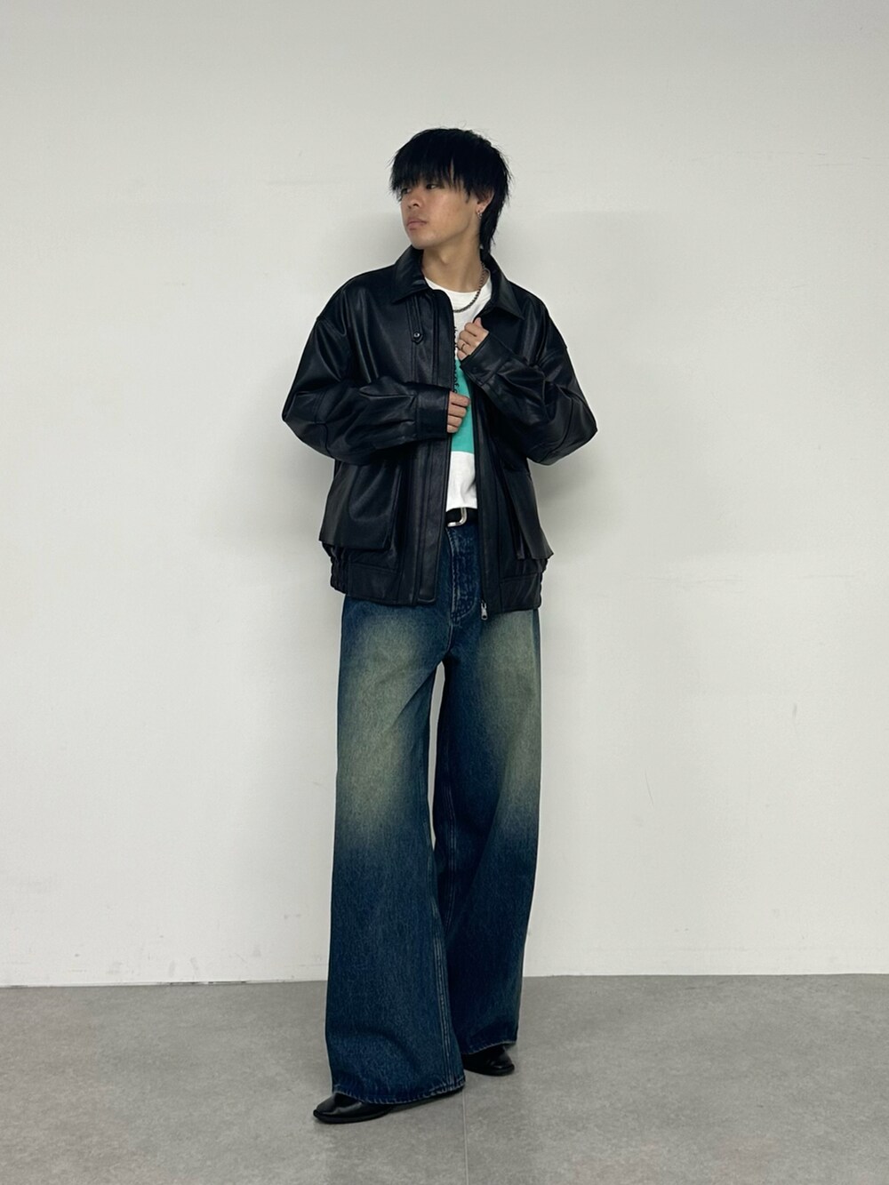 ブラック系のブルゾン、ホワイト系のTシャツ/カットソー、ブルー系のデニムパンツを着用したメンズの夏コーディネートの5枚目の写真