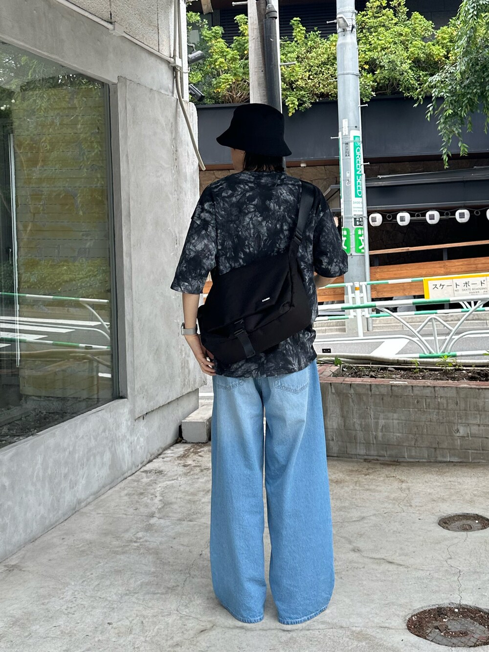 ブラック系のTシャツ/カットソー、ブラック系のメッセンジャーバッグ、ブルー系のデニムパンツを着用したメンズの夏コーディネートの3枚目の写真