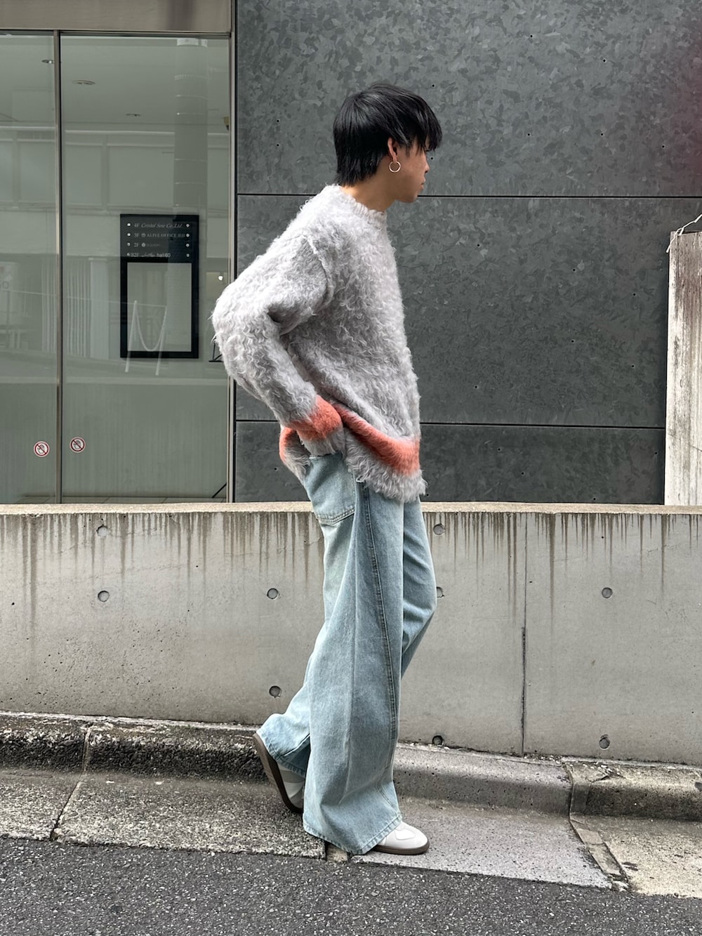 グレー系のニット/セーター、ブルー系のデニムパンツ、ホワイト系のスニーカーを着用したメンズの秋コーディネートの5枚目の写真