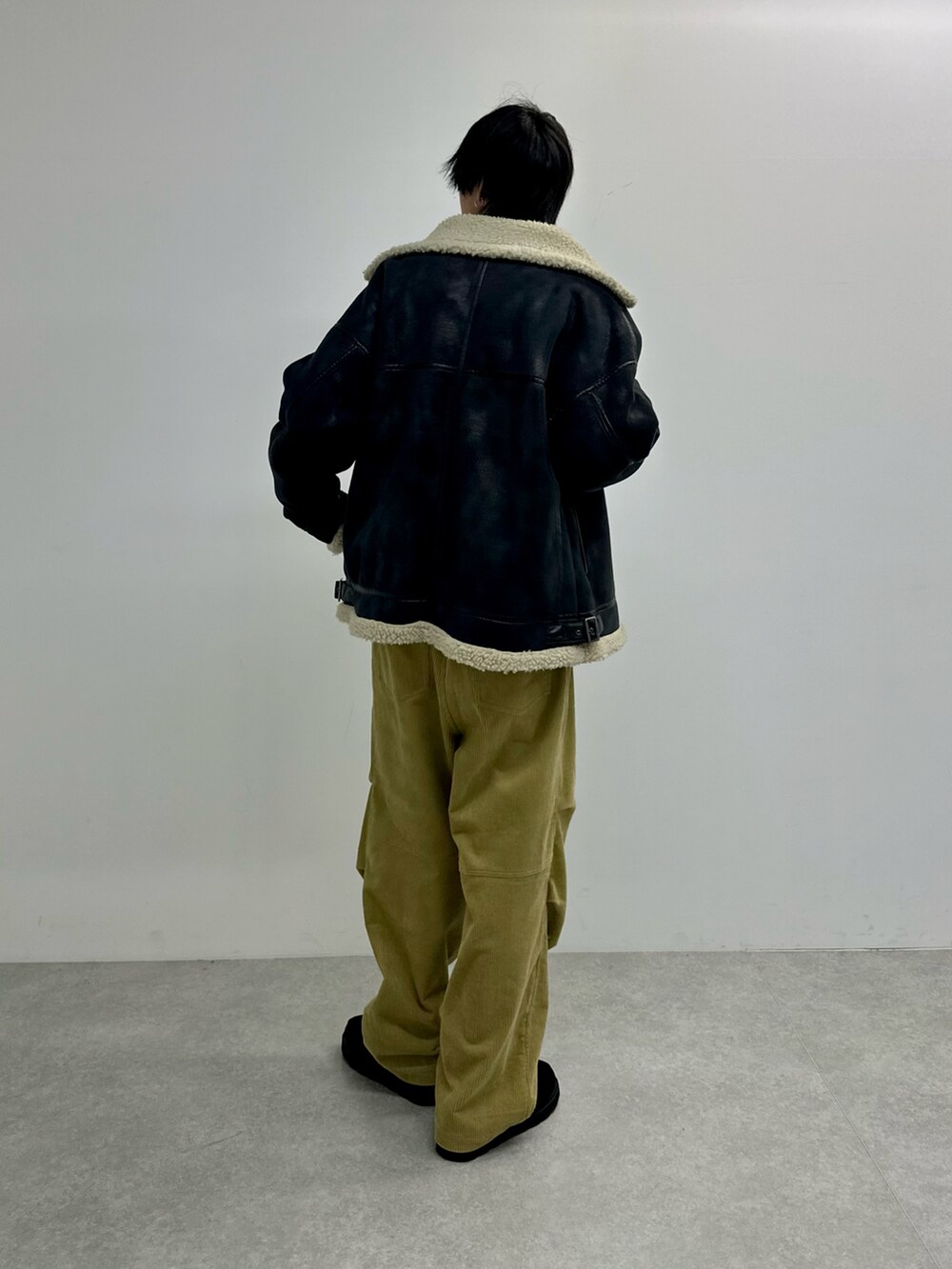 ブラック系のムートンコート、ベージュ系のその他パンツ、ブラック系のモカシン/デッキシューズを着用したメンズの秋コーディネートの2枚目の写真