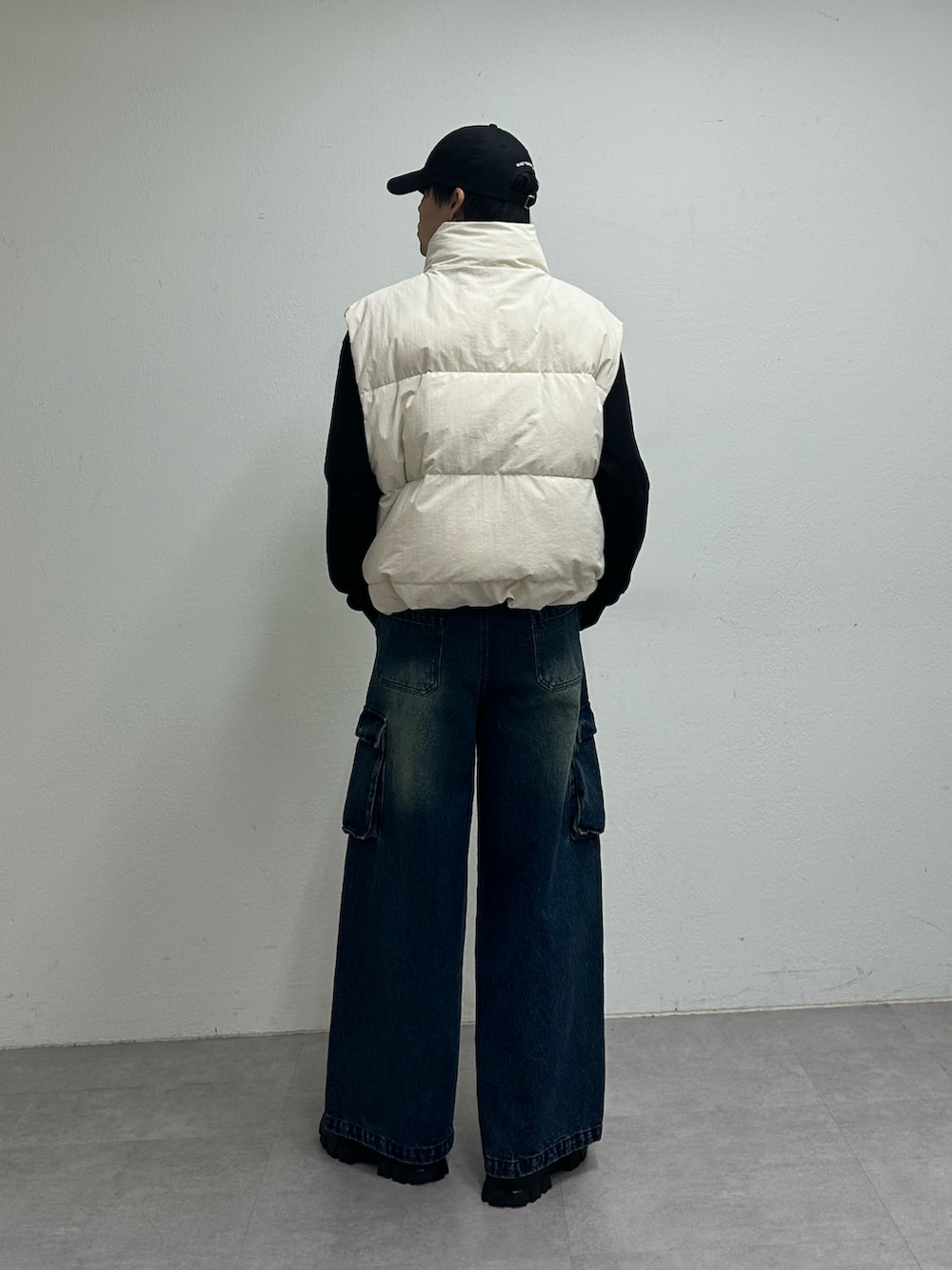 ホワイト系のダウンベスト、ブルー系のデニムパンツ、ブルー系のキャップを着用したメンズの夏コーディネートの3枚目の写真