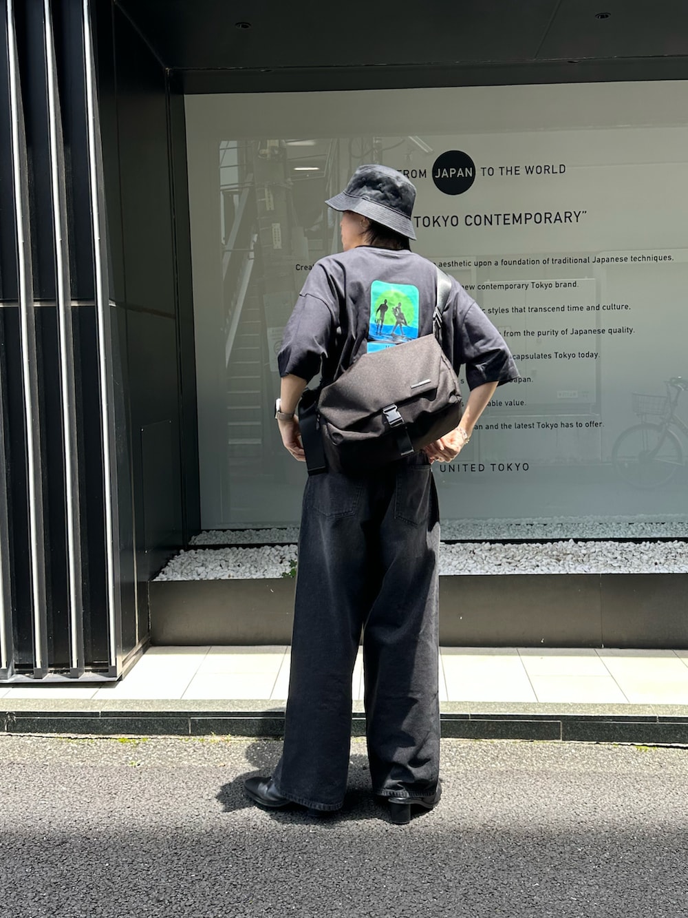 ブラック系のメッセンジャーバッグ、ブラック系のTシャツ/カットソー、ブラック系のデニムパンツを着用したメンズの夏コーディネートの2枚目の写真