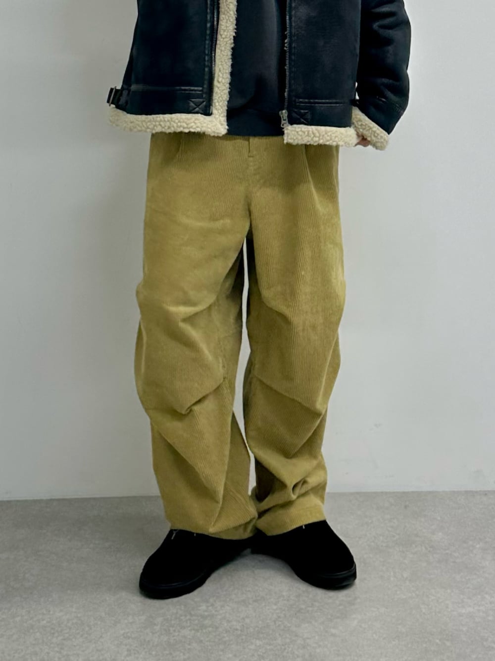 ブラック系のムートンコート、ベージュ系のその他パンツ、ブラック系のモカシン/デッキシューズを着用したメンズの秋コーディネートの3枚目の写真