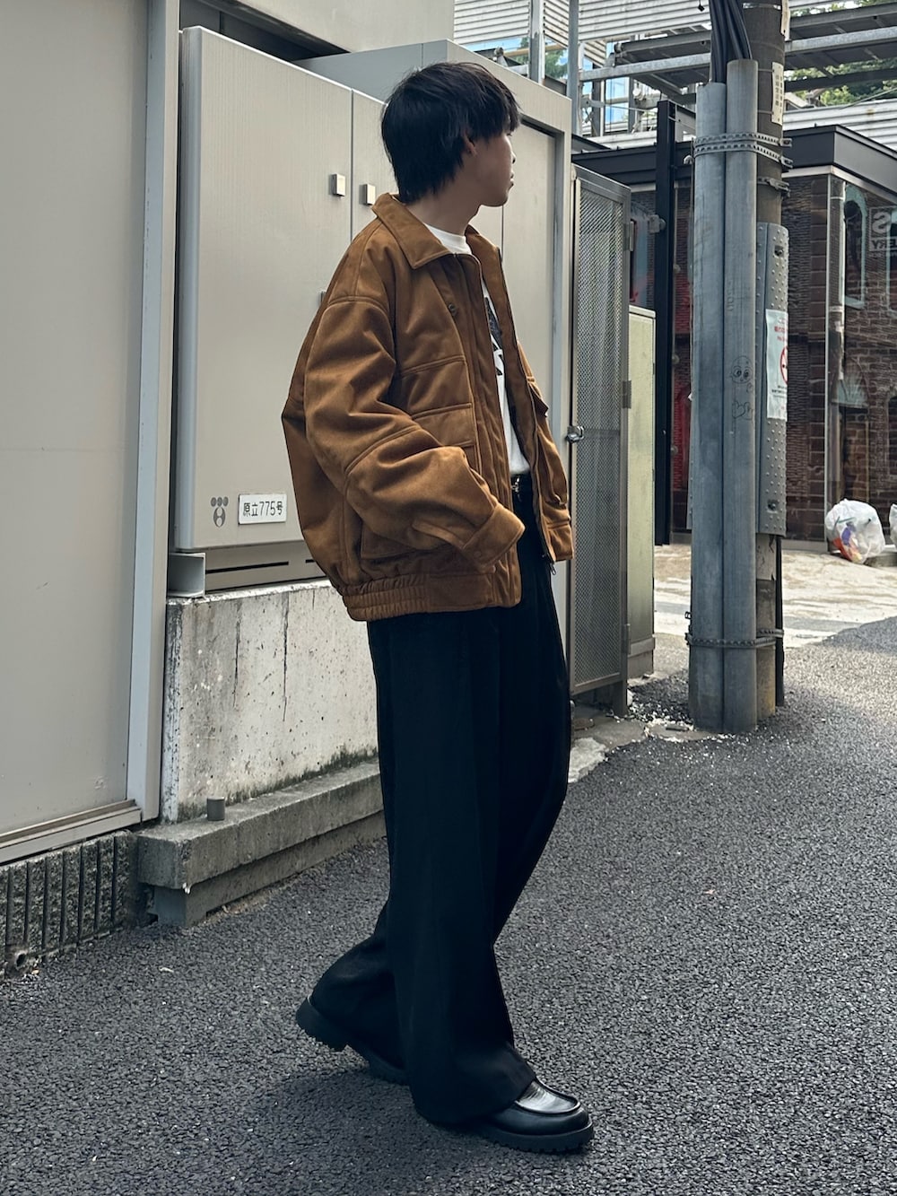 イエロー系のブルゾン、ブラック系のスラックス、ホワイト系のTシャツ/カットソーを着用したメンズの秋コーディネートの4枚目の写真
