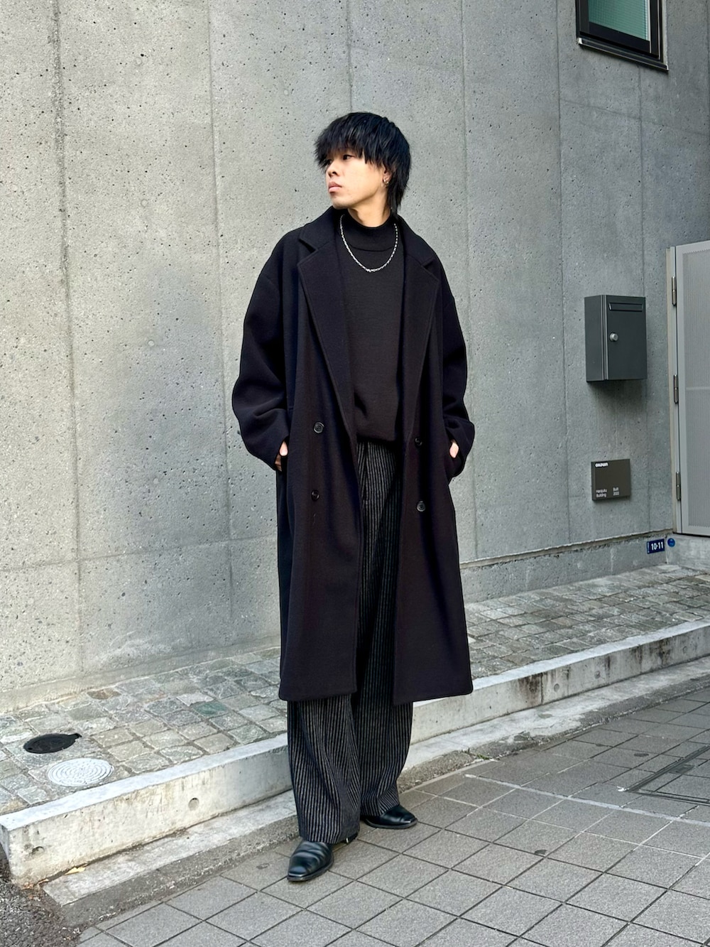 ブラック系のその他アウター、ブラック系のニット/セーター、ブラック系のスラックスを着用したメンズの冬コーディネートの2枚目の写真