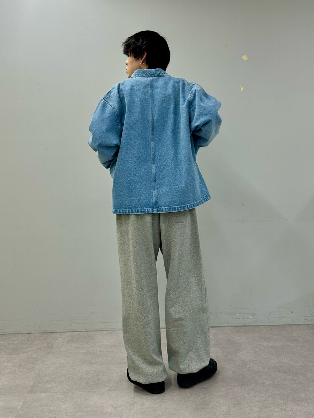 ブルー系のデニムジャケット、グレー系のスウェットパンツ、ブラック系のスニーカーを着用したメンズの冬コーディネートの3枚目の写真