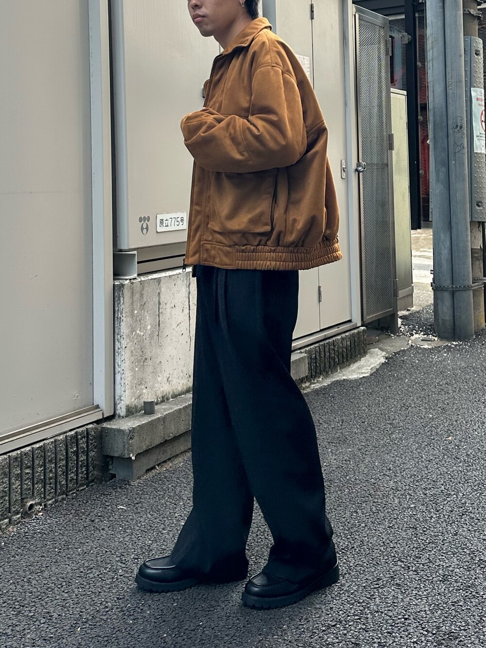 イエロー系のブルゾン、ブラック系のスラックス、ホワイト系のTシャツ/カットソーを着用したメンズの秋コーディネートの2枚目の写真