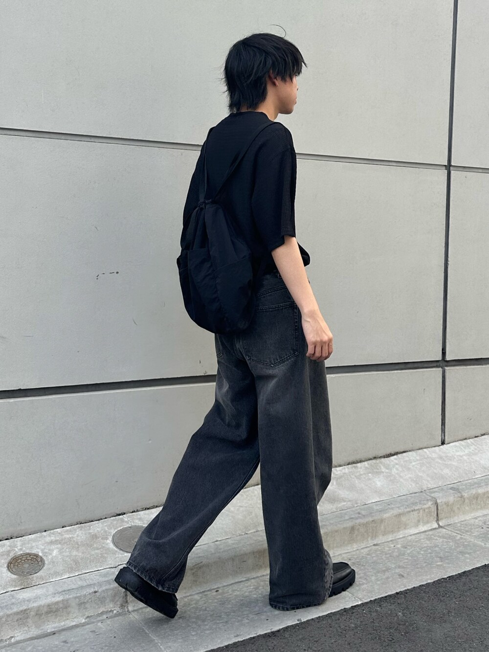 ブラック系のTシャツ/カットソー、ブラック系のバックパック/リュック、ブラック系のデニムパンツを着用したメンズの春コーディネートの3枚目の写真