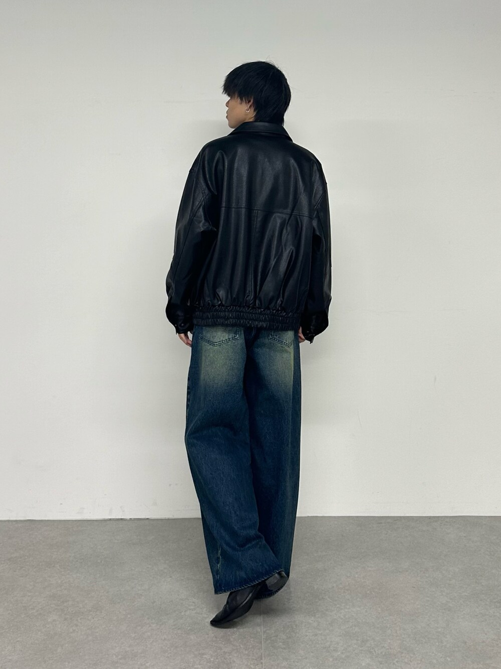 ブラック系のブルゾン、ホワイト系のTシャツ/カットソー、ブルー系のデニムパンツを着用したメンズの夏コーディネートの3枚目の写真