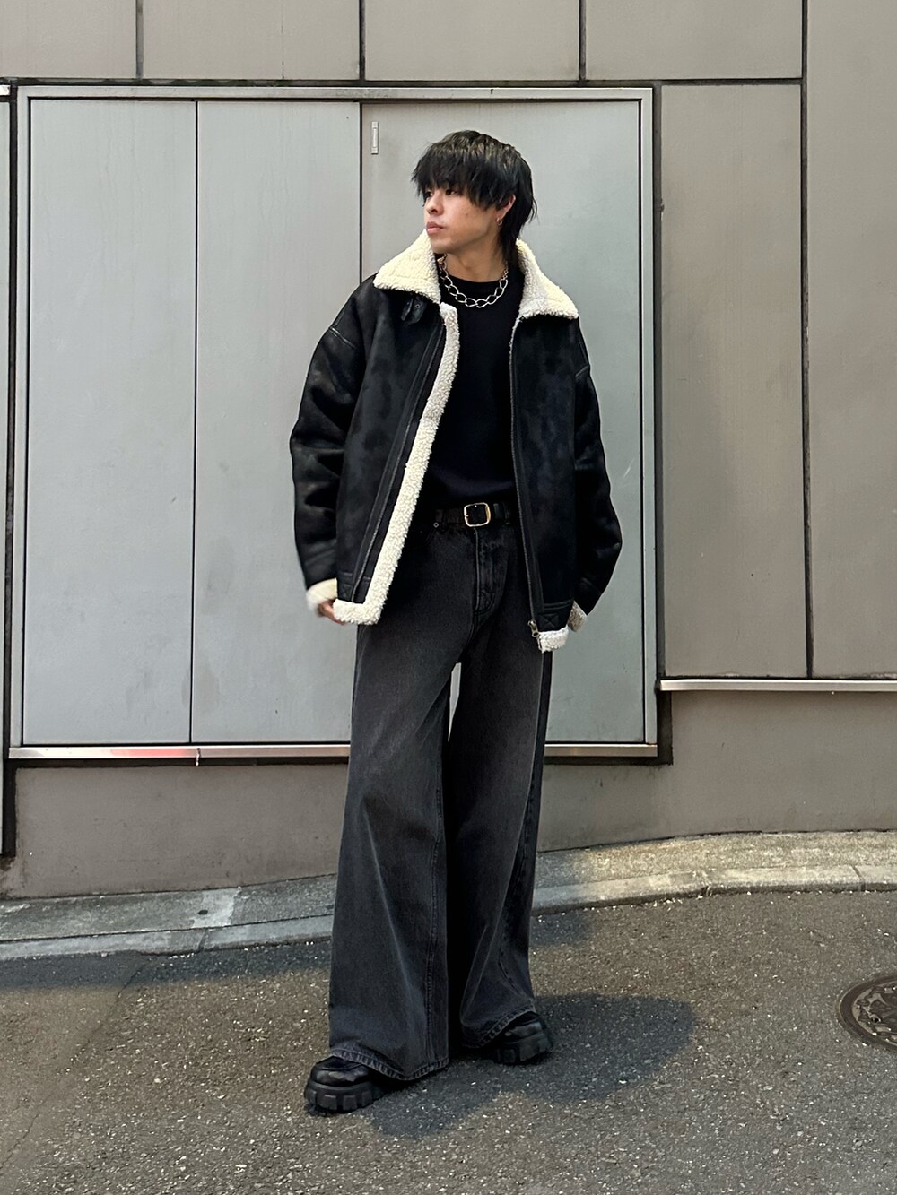 ブラック系のムートンコート、ブラック系のニット/セーター、ブラック系のデニムパンツを着用したメンズの冬コーディネートの5枚目の写真