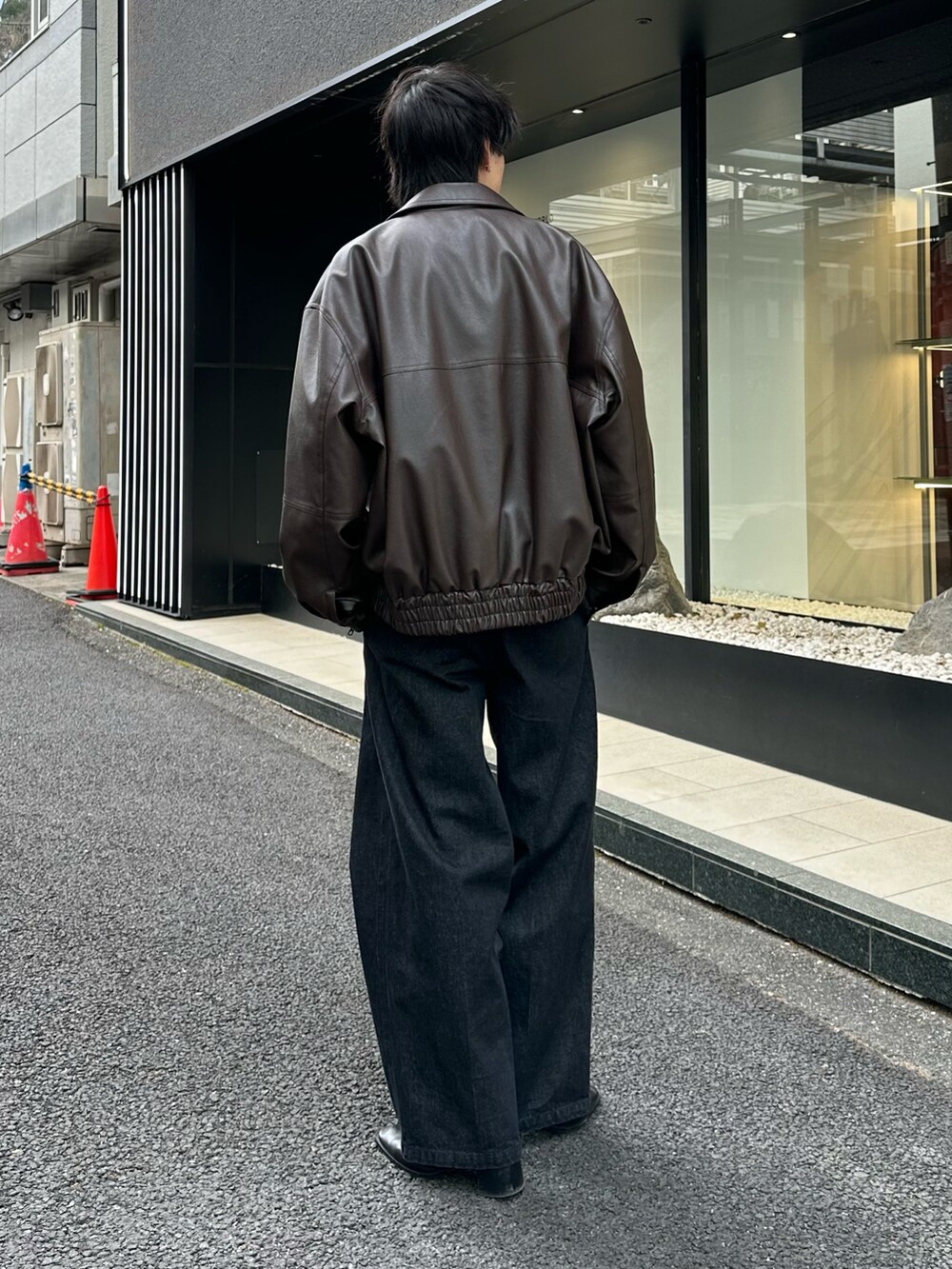 ブラック系のブルゾン、ホワイト系のTシャツ/カットソー、ブラック系のデニムパンツを着用したメンズの冬コーディネートの3枚目の写真