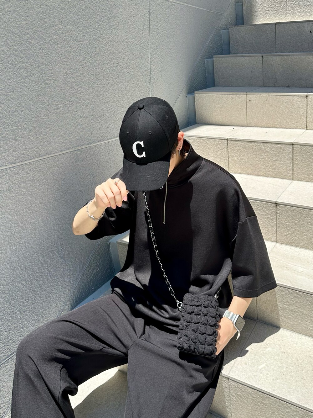 ブラック系のスラックス、ブラック系のTシャツ/カットソー、ブラック系のショルダーバッグを着用したメンズの夏コーディネートの2枚目の写真