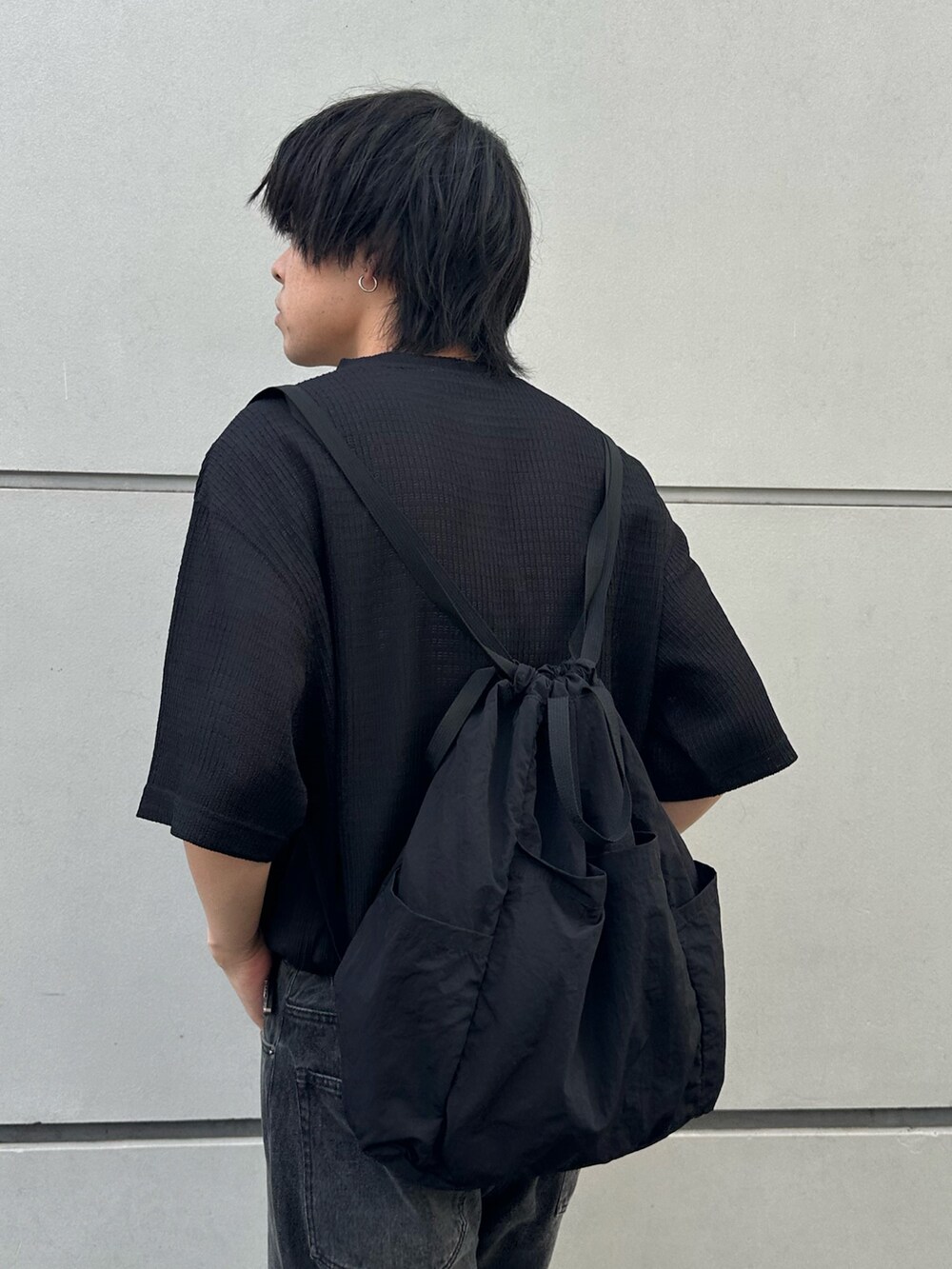ブラック系のTシャツ/カットソー、ブラック系のバックパック/リュック、ブラック系のデニムパンツを着用したメンズの春コーディネートの2枚目の写真