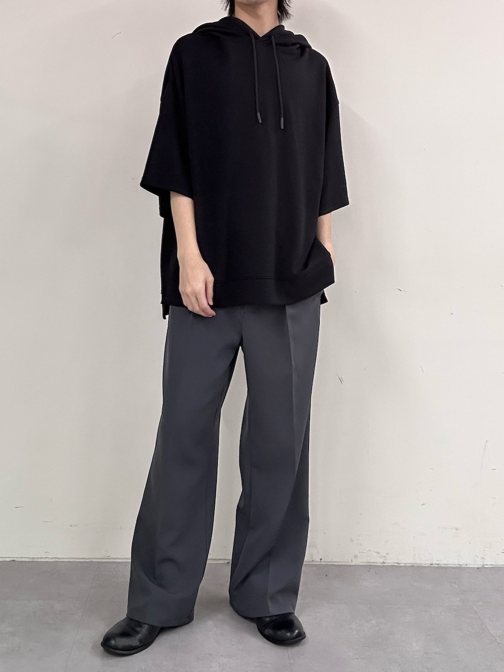 グレー系のスラックス、ブラック系のパーカーを着用したメンズの春コーディネートの2枚目の写真