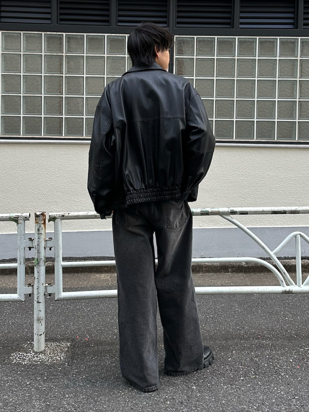 ブラック系のデニムパンツ、ブラック系のブルゾン、グレー系のTシャツ/カットソーを着用したメンズの冬コーディネートの3枚目の写真