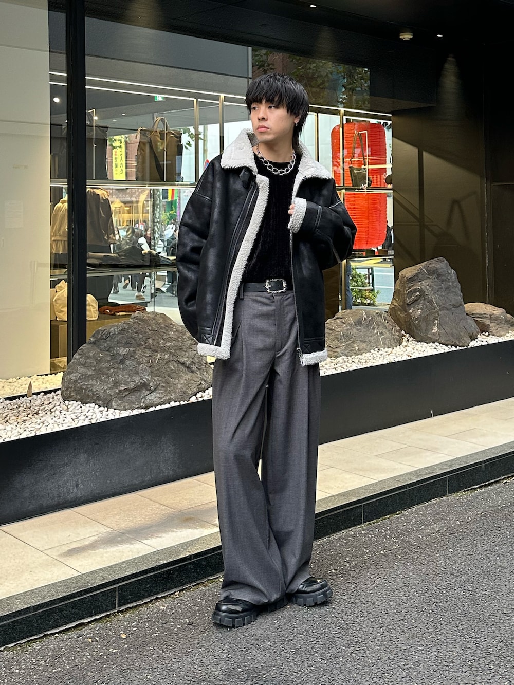 ブラック系のムートンコート、ブラック系のTシャツ/カットソー、グレー系のスラックスを着用したメンズの冬コーディネートの3枚目の写真