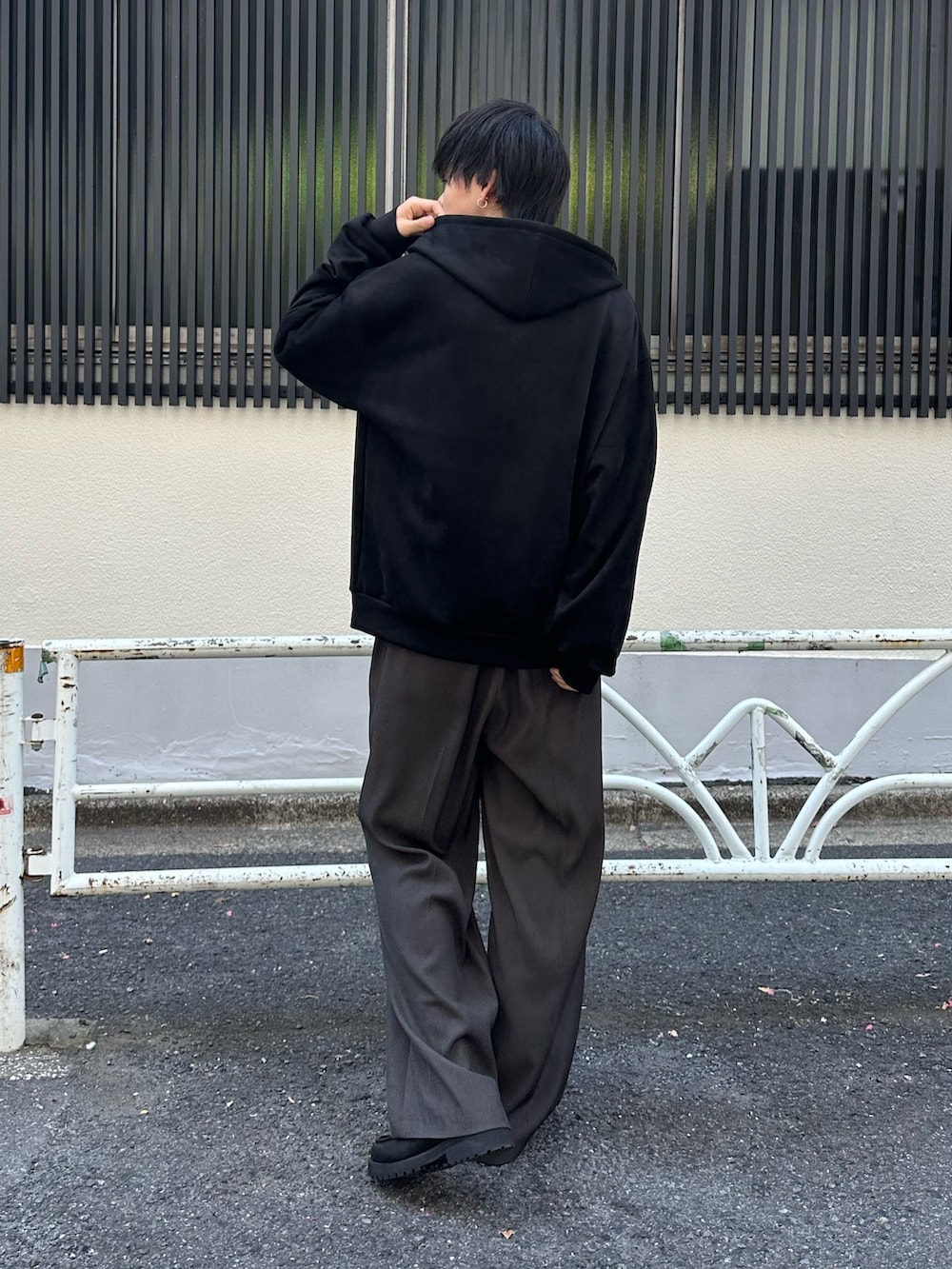 ブラック系のパーカー、グレー系のスラックス、ブラック系のドレスシューズを着用したメンズの夏コーディネートの3枚目の写真