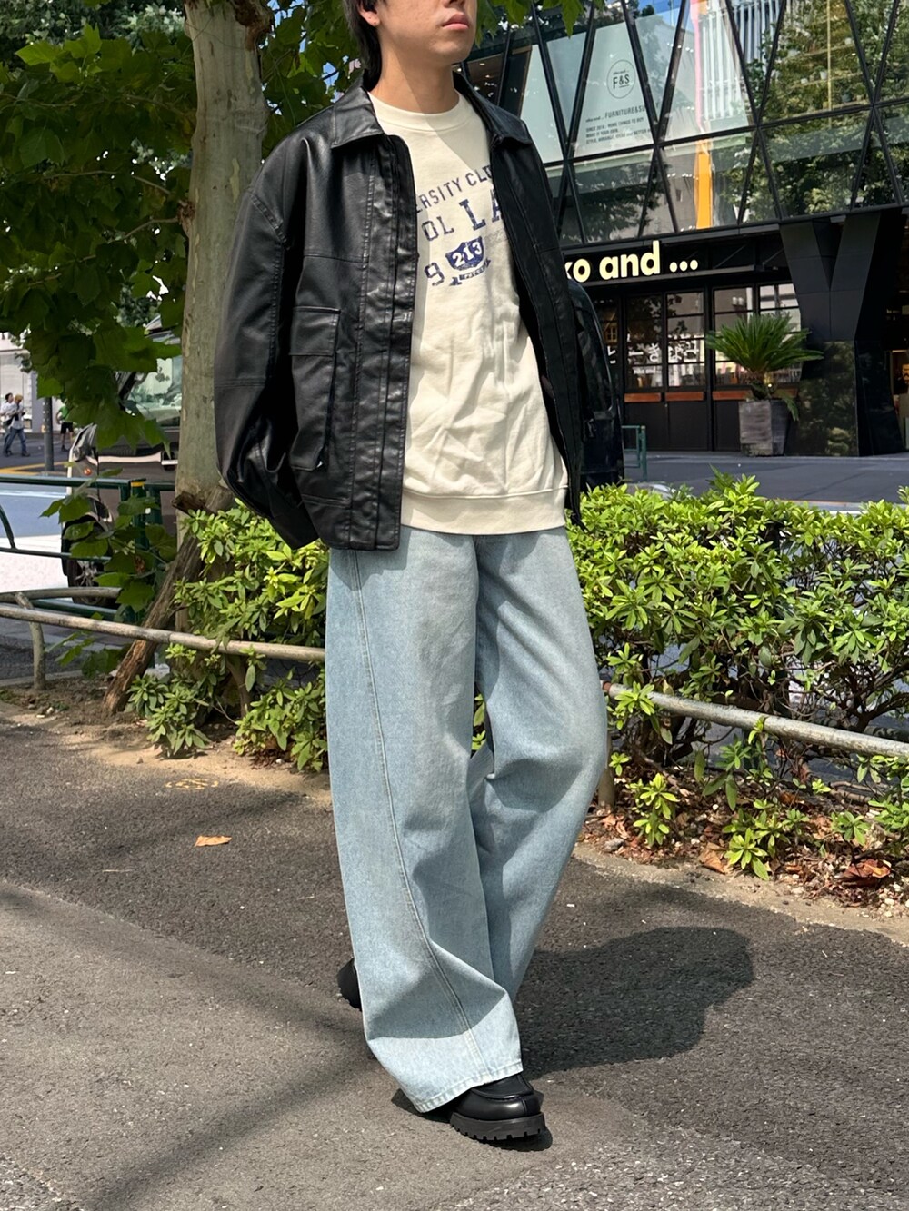 ブラック系のブルゾン、ホワイト系のスウェット、ブルー系のデニムパンツを着用したメンズの秋コーディネートの5枚目の写真