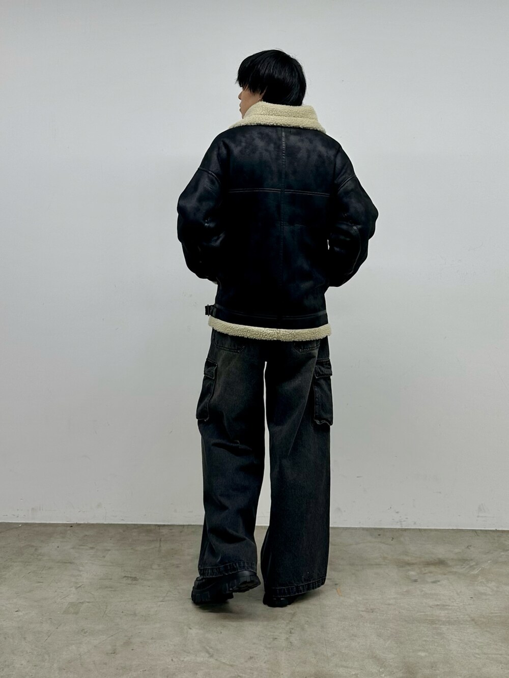 ブラック系のデニムパンツ、ブラック系のムートンコート、ホワイト系のニット/セーターを着用したメンズの秋コーディネートの3枚目の写真