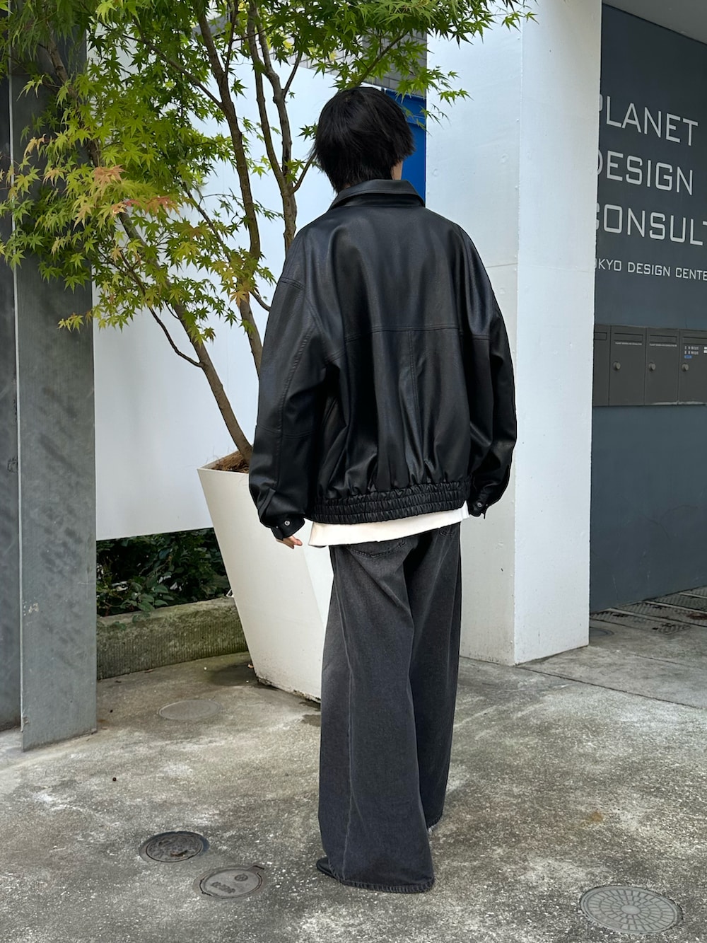 ブラック系のブルゾン、ホワイト系のスウェット、ブラック系のデニムパンツを着用したメンズの秋コーディネートの2枚目の写真