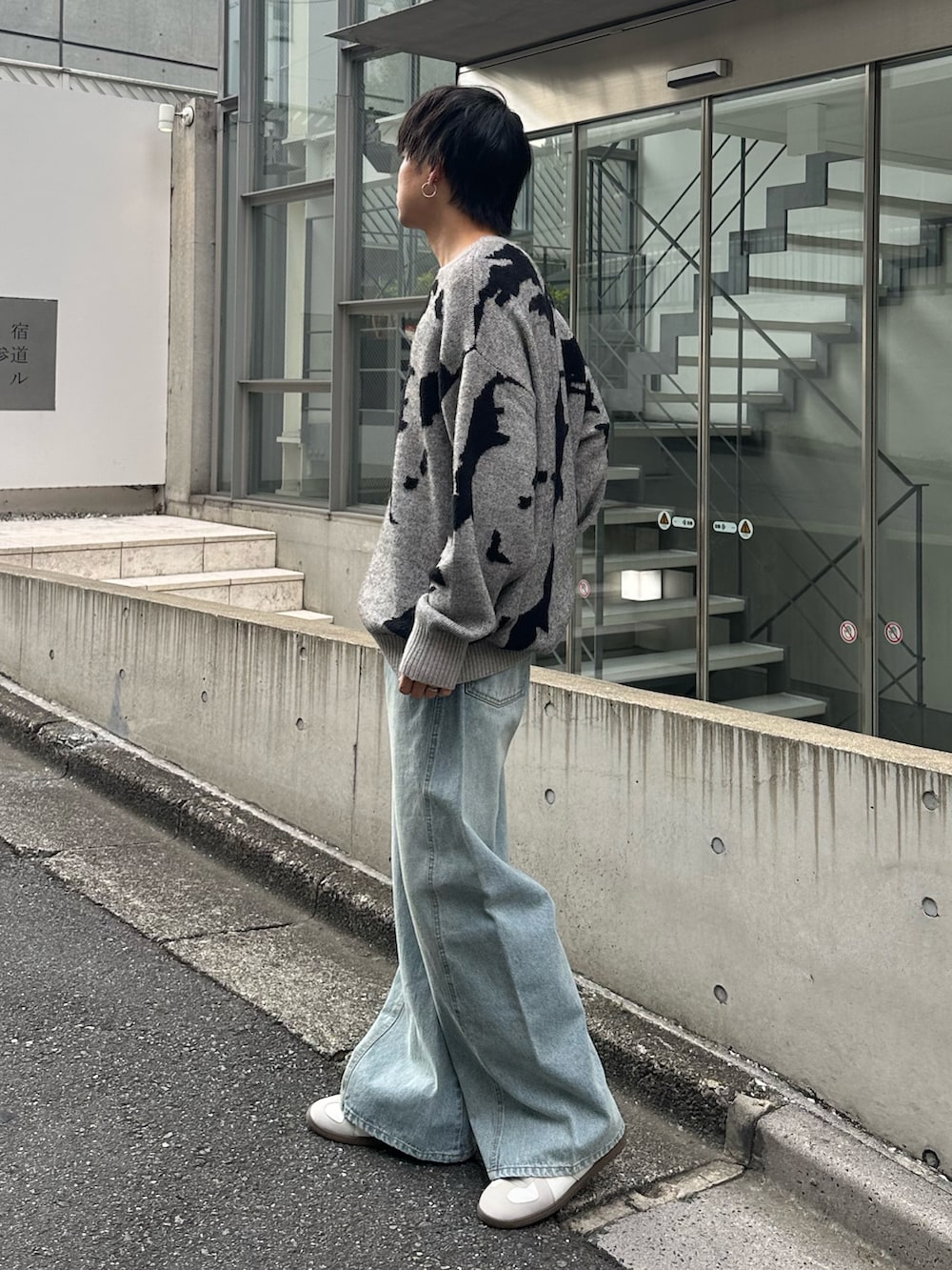 グレー系のニット/セーター、ブルー系のデニムパンツ、ホワイト系のスニーカーを着用したメンズの秋コーディネートの3枚目の写真