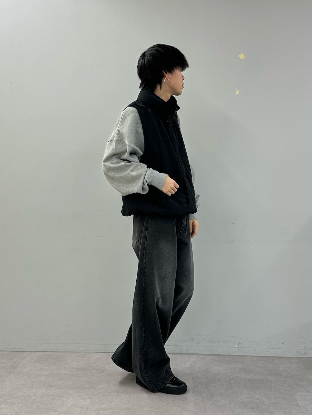 ブラック系のベスト、グレー系のスウェット、ブラック系のデニムパンツを着用したメンズの冬コーディネートの4枚目の写真