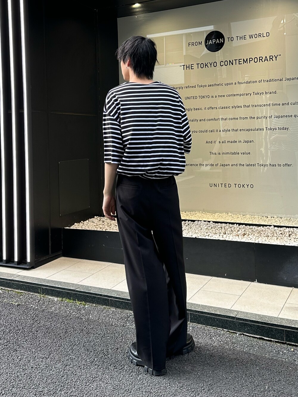 ブラック系のTシャツ/カットソー、ブラック系のスラックスを着用したメンズの春コーディネートの2枚目の写真