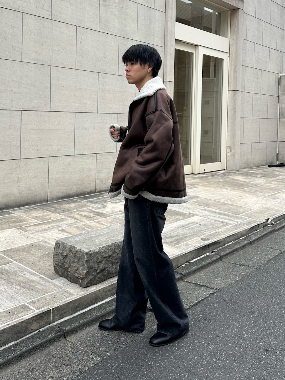 ブラウン系のムートンコート、ブラック系のTシャツ/カットソー、ブラック系のデニムパンツを着用したメンズの秋コーディネートの2枚目の写真